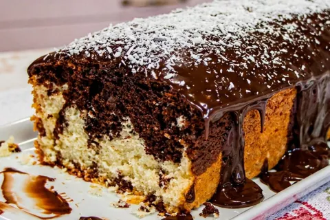 Bolo mesclado de coco com chocolate e cobertura cremosa que 